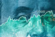 Closeup Benjamin Franklin face on USD banknote with stock market chart graph for currency exchange and global trade forex concept.