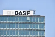 BASF-Logo auf einem modernen Glasbürogebäude unter blauem Himmel.
