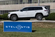 Jeep Grand Cherokee SUV bianco davanti alla sede Stellantis con logo aziendale visibile