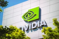 NVIDIA logo displayed on the exterior wall of a modern office building surrounded by green trees.