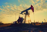 Oil pumpjack operating in an oil field at sunrise.