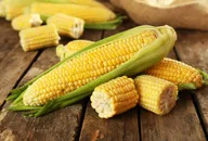 Image of several corn cobs on a wooden surface