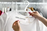 Cotton clothing on a rail being examined by a shopper