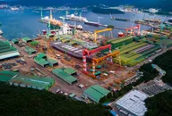 Vista aerea di un grande cantiere navale con gru e navi in costruzione.