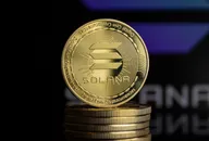 Gold Solana cryptocurrency coin placed on a stack of coins with a blurred dark background