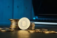 Solana cryptocurrency coin placed on stacked coins with a laptop in the background