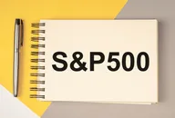 Notebook with “S&P 500” text placed on a desk next to a pen