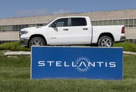 Logo Stellantis su insegna blu con pickup RAM bianco esposto sopra davanti a un edificio aziendale