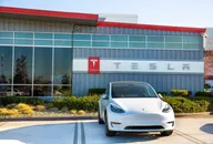 Tesla car parked in front of a Tesla showroom building