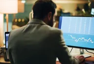 Trader überprüft Finanzcharts und Börsenmarktdaten an einem Desktop-Computer