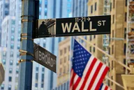 Znak Wall Street z amerykańską flagą i budynkami miasta w tle