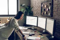 Female trader at a desk with market screens