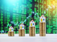 Model houses and coins on table representing finance