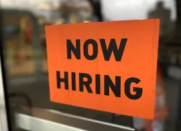 “now hiring” sign posted on business door