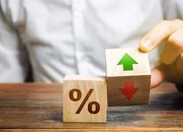 A businessman holds wooden blocks with percentages and up or down arrows. Mortgage and loan rates. Interest rate, shares, rating. The concept of business and finance.