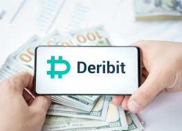 Deribit's logo on a phone, which is in front of cash