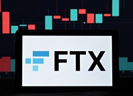 The FTX name and logo on a mobile phone in front of a price graph 