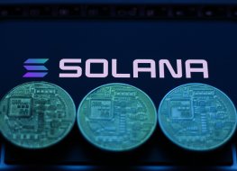 Solana logo displayed on a phone screen with representation of cryptocurrencies
