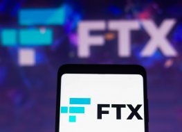 The FTX crypto derivatives exchange logo is displayed on a smartphone screen and in the background
