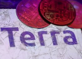 Terra logo displayed on a phone screen is seen through a broken glass with representation of cryptocurrency in this illustration photo