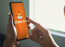 A woman holds a smartphone with the Shiba Inu (SHIB) logo displayed on the screen