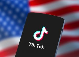 A image of TikTok on a smartphone with the US flag in the background