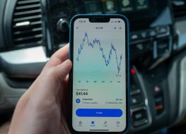 hand holding an iPhone displaying chart of the price of Chainlink cryptocurrency 