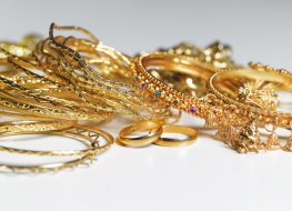 A variety of gold jewellery against a plain background