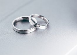 Two platinum wedding bands on a grey background