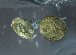 Two golden bitcoins drop into a tank of water