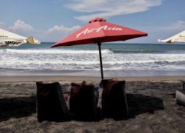 Empty beach chairs under AirAsia beach umbrella on Echo Beach, Bali