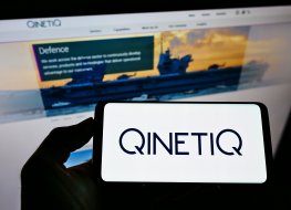 QinetiQ logo on a mobile screen in the foreground of the company website on a computer screen