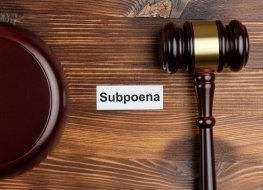 A courtroom gavel lies next to the word ‘subpoena’