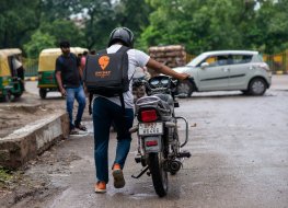 An image of a Swiggy delivery agent pushing his bike while at work