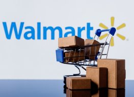 Toy shopping cart and boxes in front of Walmart logo.