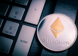 Silver Ether coin with gold Ethereum symbol on a laptop keyboard