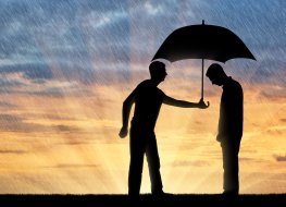 A silhouette of a man holding an umbrella over another man's head