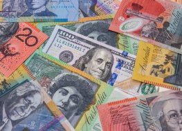 A hundred US dollar bill from and colorful Australian dollars banknotes, symbolizing the AUD/USD exchange rate