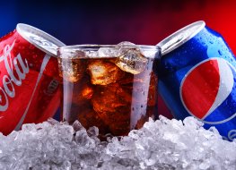 Pepsi and Coca-cola cans with ice Two cans of world's most popular soft drinks: Coca Cola and Pepsi with crushed ice