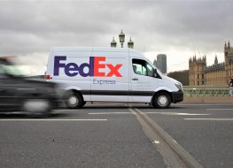 FedEx stock forecast: Set to deliver success in 2023? London, UK / March, 2020 / A FedEx courier van parked up in Westminster bridge, with an abstract London taxi driving by. Logo clearly in focus, and you can see the House's of Parliament in view.