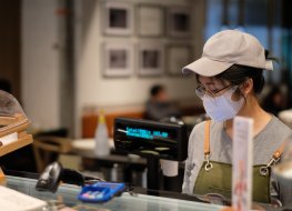An Asian woman in a cafe wearing a surgical mask