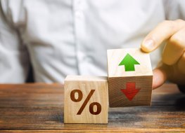 A businessman holds wooden blocks with percentages and up or down arrows. Mortgage and loan rates. Interest rate, shares, rating. The concept of business and finance.
