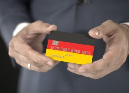Businessman takes plastic bank card with printed flag of Gemany, fictional numbers