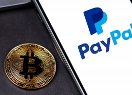 Paypal logo in a smartphone, next to a bitcoin symbol 