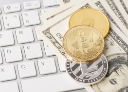 Cryptocurrency tokens sit on top of a stack of dollars placed on a keyboard