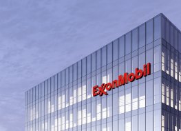 Exxon Mobil stock forecast: Will energy giant rebound to record high? ExxonMobil Signage Logo on Top of Glass Building. Workplace of Gas and Oil Company in High-rise Office Headquarter.