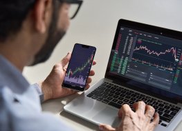 Trader using mobile phone and laptop for trading