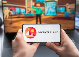 Russia Moscow 30.05.2021.Logo,screenshot of blockchain nft ethereum cryptocurrency game Decentraland in laptop,mobile phone.Man playing with crypto coins,token MANA.Earning digital money.Lands,heroes.