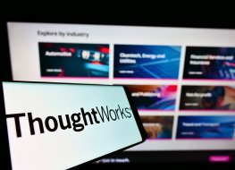 Photo of a smartphone with the logo of Thoughtworks in front of a screen displaying the company's website