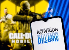 Activision Blizzard logo on smartphone screen. A frame from the Call of Duty on the background.